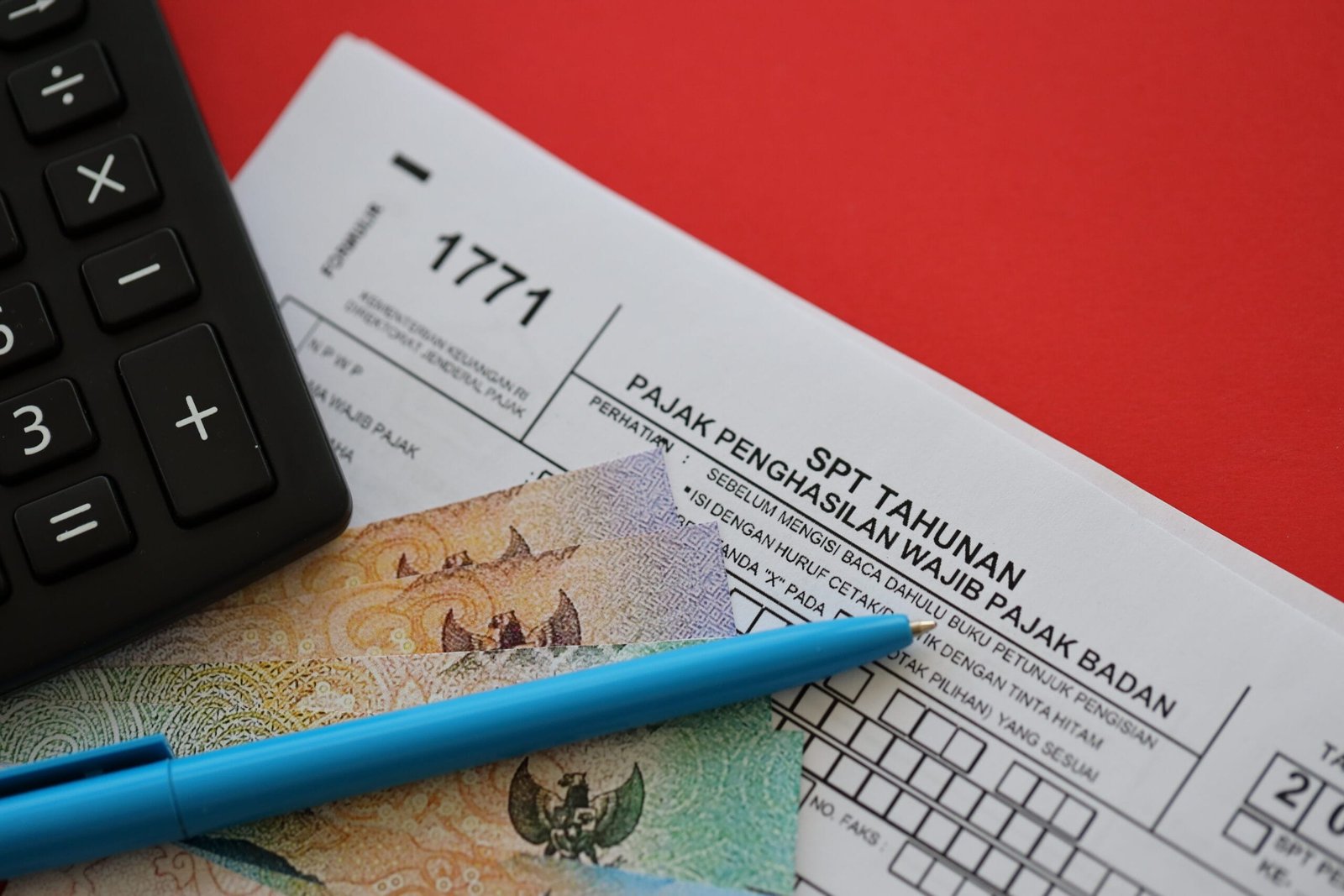 Kalkulator, formulir pajak, dan pena untuk menghitung pajak terutang