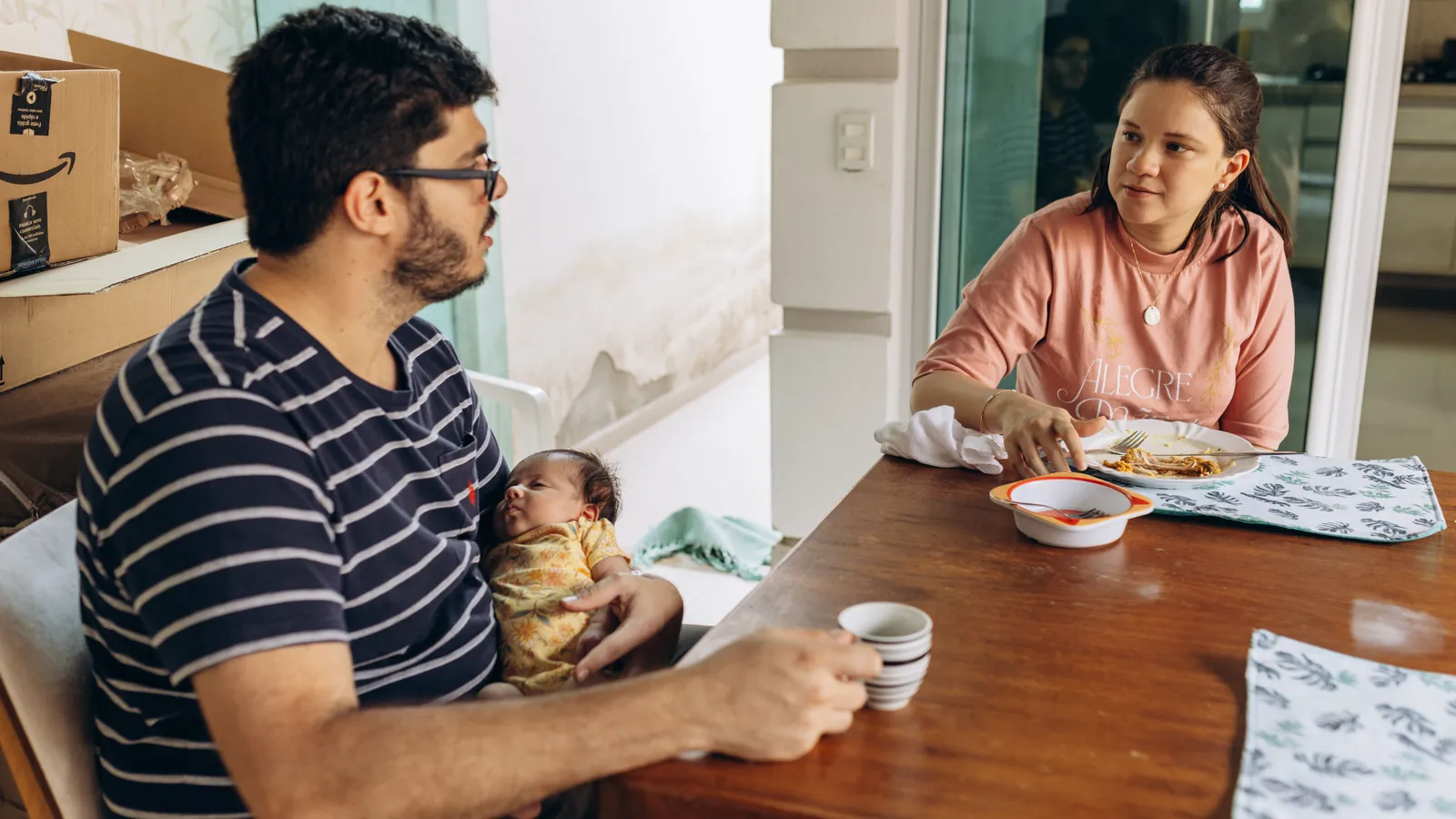 Pasangan muda bersama anak menata dokumen keluarga di meja makan, menggambarkan penentuan status PTKP